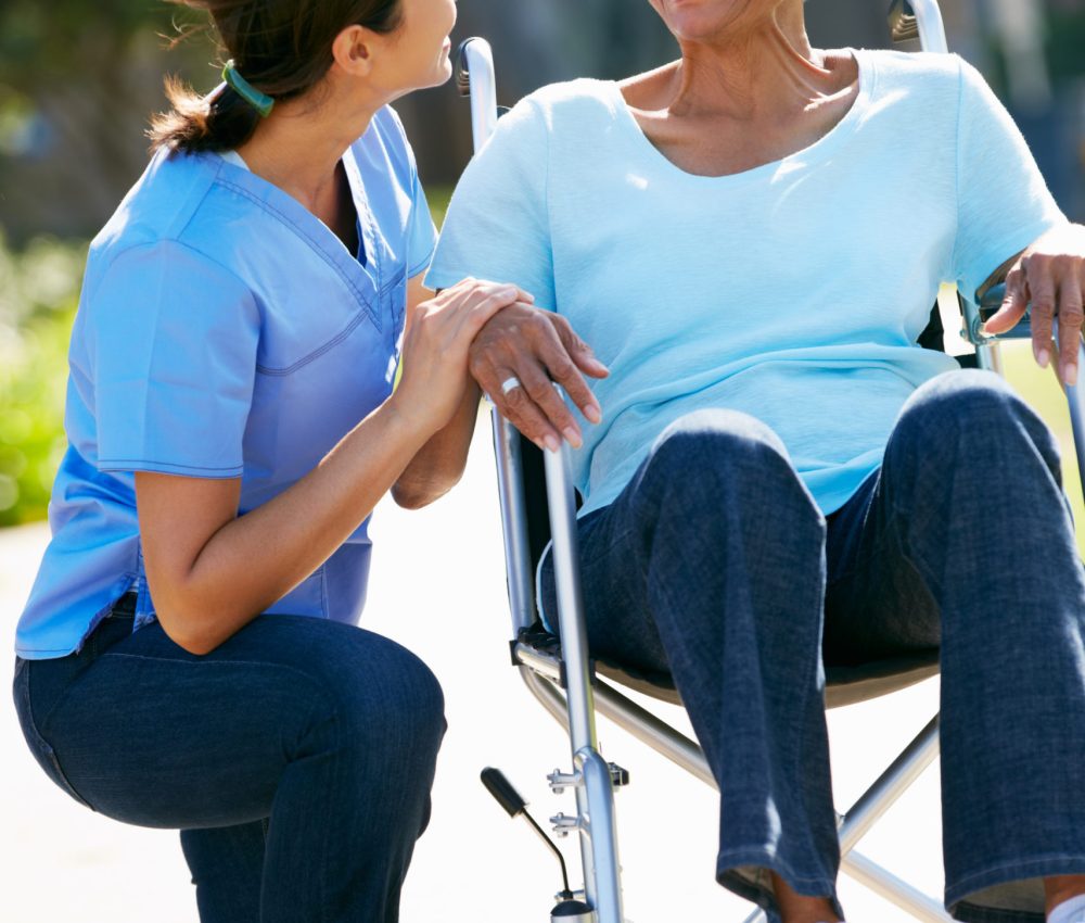 Carer Pushing Senior Woman In Wheelchair